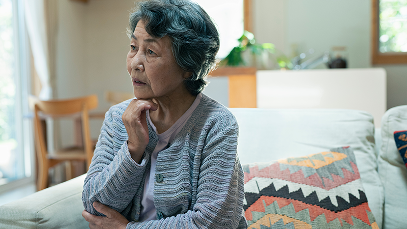 リビングで悩むシニア女性
