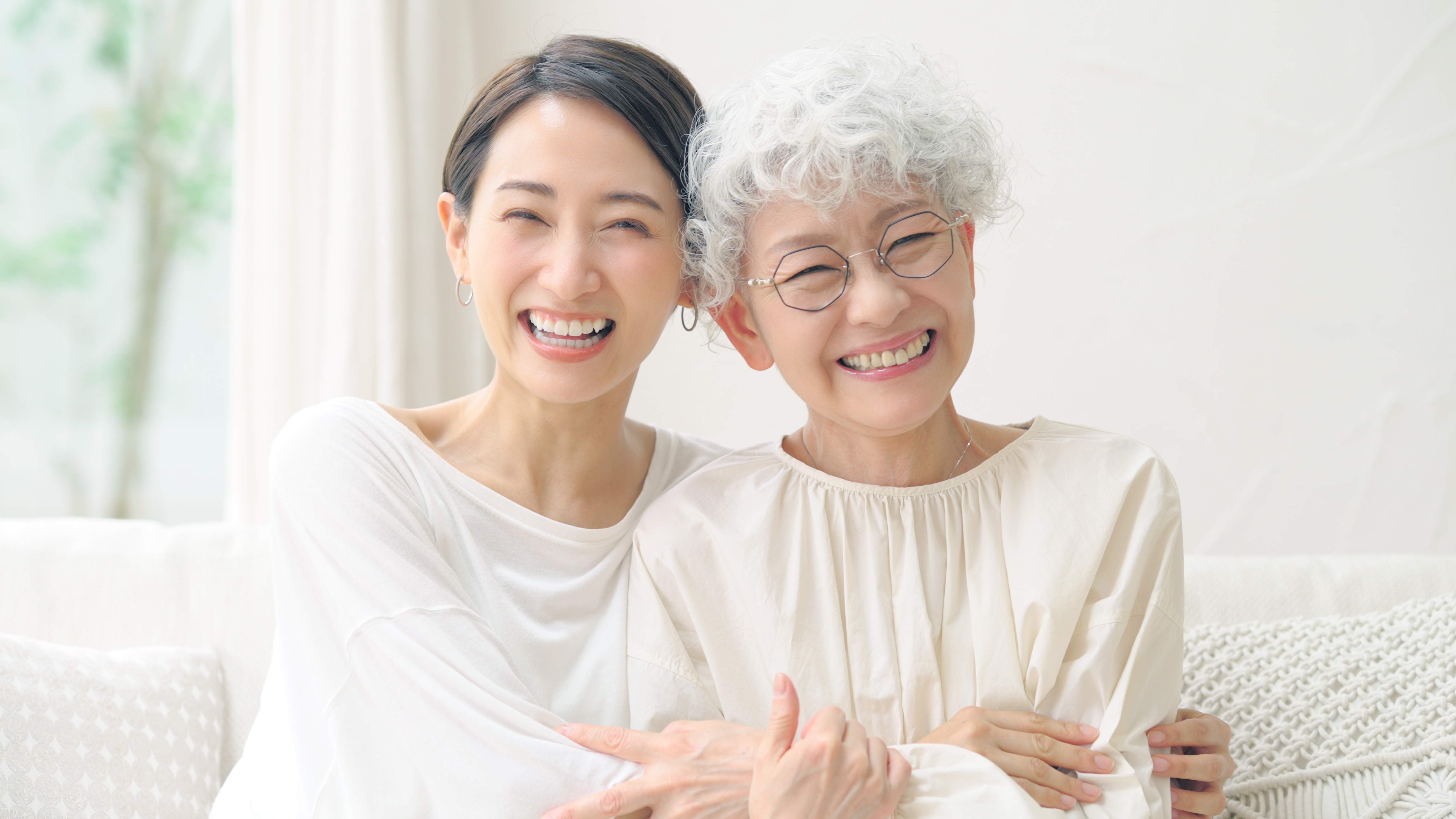 笑顔で寄り添うシニアの母親と50代の娘