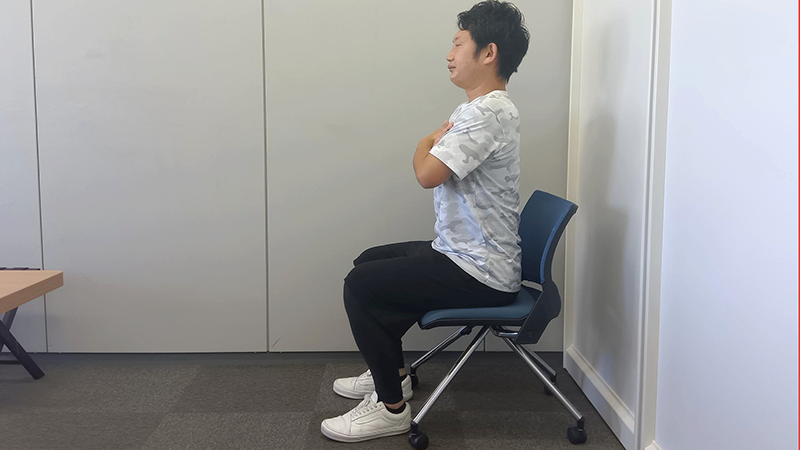 いすに座り腕を組む男性