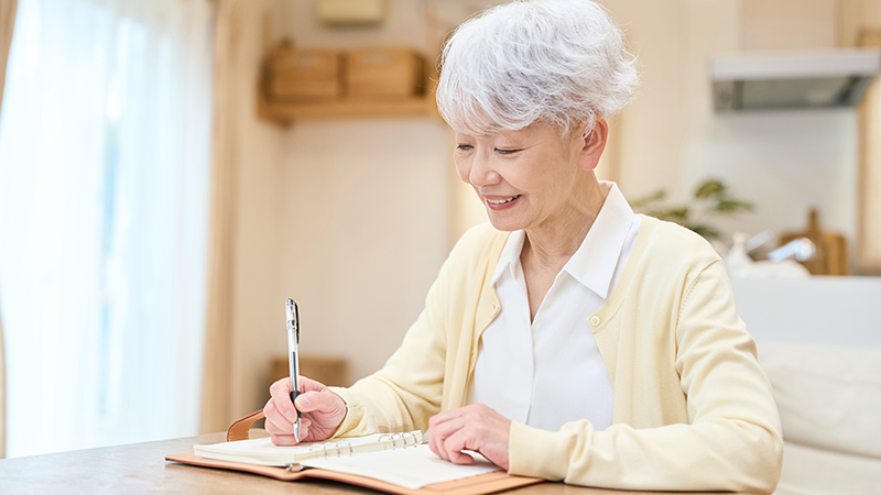 手帳とペンを持って笑顔で予定を立てるシニア女性