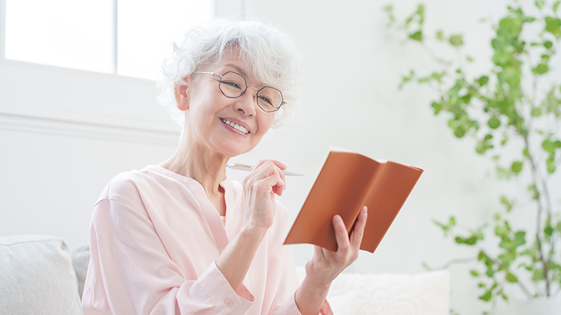 手帳にメモするシニア女性