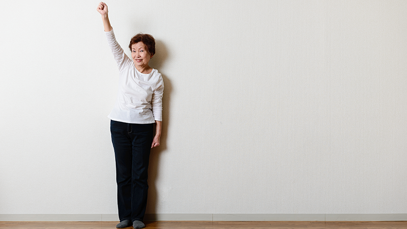 腕を上げている高齢女性
