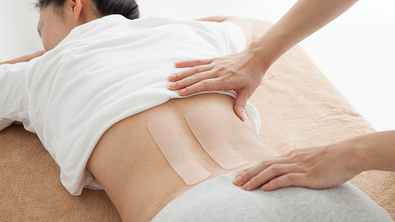 腰にシップを張る高齢女性