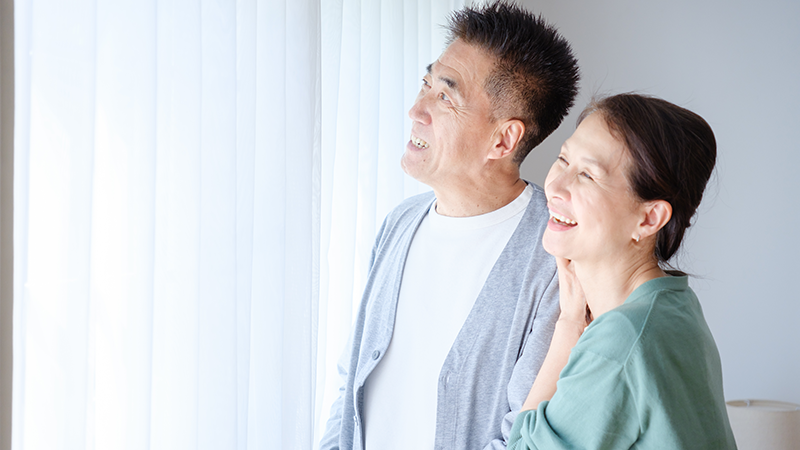 自宅のリビングで笑顔で元気よく過ごす日本人のシニア夫婦のイメージ